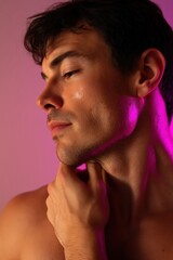 a sensual gay male model with glowing skin and soft eyes, shirtless, posing with one hand touching his neck, standing in soft pink lighting, minimal background,