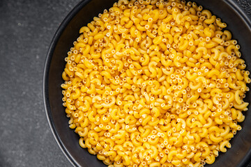 Macaroni pasta raw coquillette appetizer dish organic product fresh tasty gourmet food background on the table rustic food top view copy space