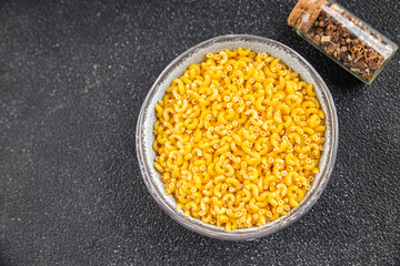 Macaroni pasta raw coquillette appetizer dish organic product fresh tasty gourmet food background on the table rustic food top view copy space