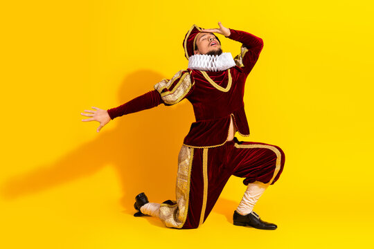 Male actor dressed as a nobleman in a red costume posing on yellow