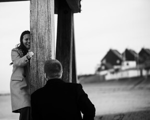 Young caucasian couple enjoying seaside walk under wooden pier