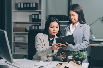 Asian Businesswoman Using laptop computer and working at office with calculator document on desk, doing planning analyzing the financial report, business plan investment, finance analysis concept.