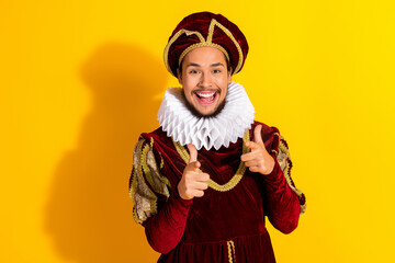 Cheerful Young Man in Royal Renaissance Costume Against a Bright Yellow Background