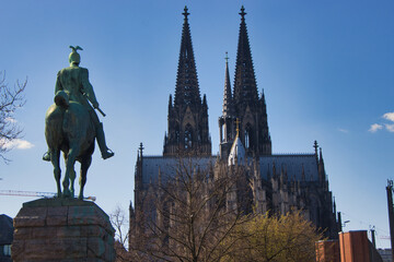 Blick auf den Kölner Dom mit Statur Hohenzollern bei gutem Wetter und blauen Himmel 