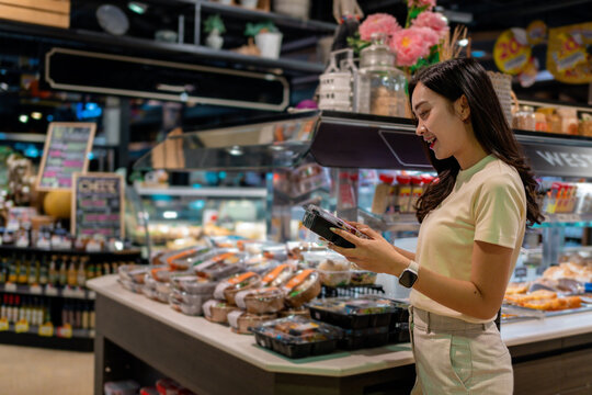 Young Woman Choosing Ready Meal in Supermarket Groceries Section