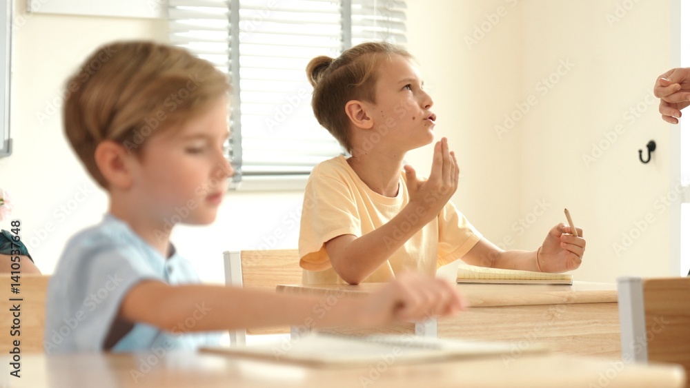 Poster beautiful teacher explaining test while caucasian boy doing classwork and listening explanation. cut