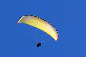 Tandem Paraglider flying in a blue sky	