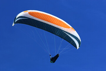 Paraglider flying in a blue sky	