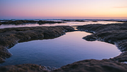 Fototapeta premium Tide pool with rocky formations reflecting sunset colors under tranquil coastal atmosphere