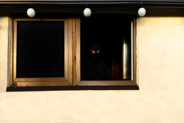 Thief in black cap covering face caught breaking into house, refugee, immigrant