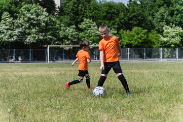 Obraz premium Two boys playing soccer on sunny green field.