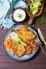 Hash browns with smoked salmon, cucumbers and yogurt. Vegetable fritters, latkes, potato cakes. Vegetable pancakes. High angle view