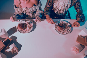 A couple in baroque costumes dining with a modern fast-food twist under elegant neon lighting.