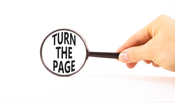 Turn the page symbol. Concept words Turn the page in beautiful magnifying glass. Beautiful white background. Businessman hand. Business motivational lifestyle turn the page concept. Copy space.