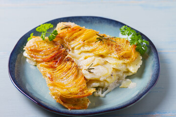Potato and onion gratin on blue plate. Scalloped potatoes or potato bake