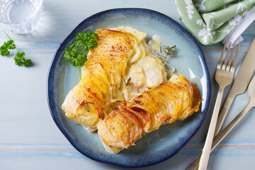 Potato and onion gratin on blue plate. Scalloped potatoes or potato bake. View from above, top view