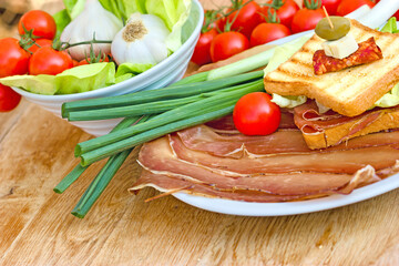 Delicious sandwich with prosciutto and pork prosciutto on plate