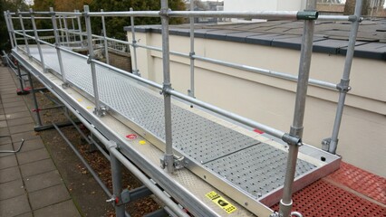 A medium closeup of an adjustable scaffold platform highlighting the integrated guardrails and nonslip surface that prevent falls and enhance worker safety during elevation tasks.
