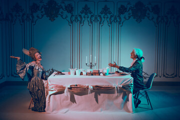 Elegant couple in baroque costumes enjoying an evening at a beautifully lit palace room