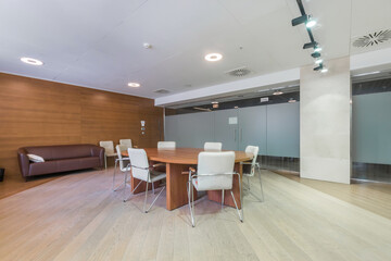 Modern office room for negotiations and meetings. Brown leather sofa, table with comfortable chairs.