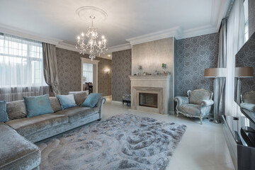 The delightful interior of the living room in the neoclassical style. Fireplace, fluffy carpet and velour sofa with pillows.