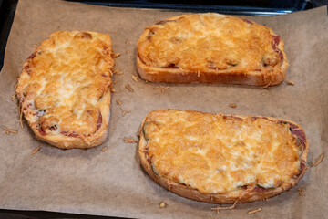 Homemade open-faced cheese sandwiches on baking tray
