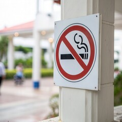 A no-smoking sign posted outdoors, promoting a smoke-free environment in a public area with blurred backgrounds of greenery and people.