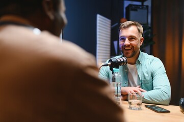 Man recording podcast using high tech microphones to interview guest, ensuring flawless video and...