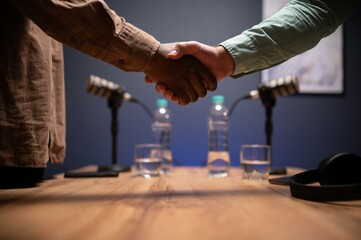 Podcasters shake hands after a good talk. Concept of podcasts and vlogs