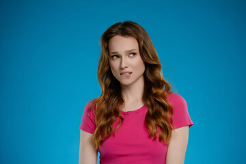 Obraz premium Woman posing in studio setting with emotional expression against a vivid blue background