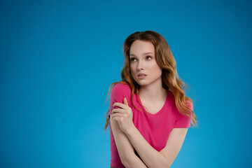 Woman poses in a studio setting with emotional expression against a solid blue background