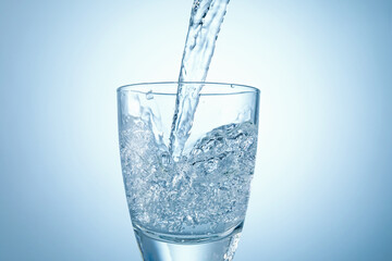 Pouring refreshing soda water into glass on light background, closeup
