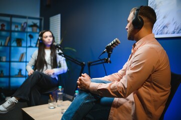 Side view of successful woman hosting podcast interviewing man while recording with professional microphones, copy space