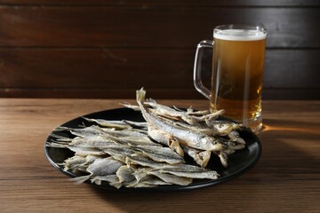 Dried salted fish and beer on wooden table, closeup