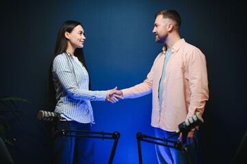 Happy podcasters man and woman shaking hands after recording podcast