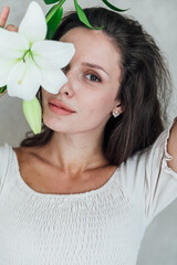 Portrait of a beautiful brunette woman in a light summer dress on a light background