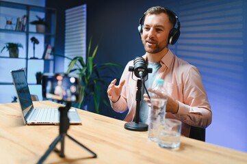 A video blogger records content in his studio. The host of the video blog is a young man who is...