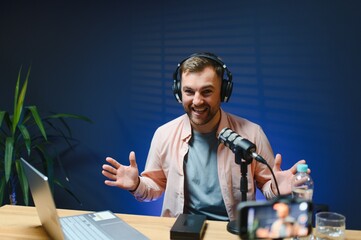 vlogger using smartphone to film podcast in studio. blogger with mobile phone, microphone and...