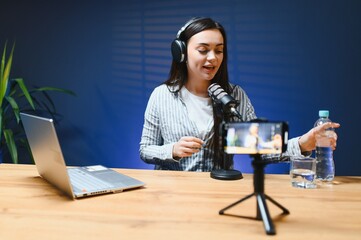 Positive female vlogger recording a video on camera sitting at desk