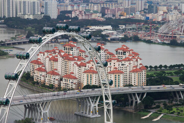 Singapore Flyer observation wheel with residential skyline and bridge over river in urban landscape