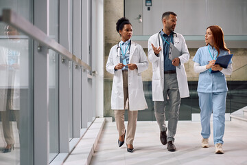 Team of healthcare experts talking while walking through the hospital.