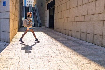girl with a backpack. happy young woman walking on European street at sunset time. female traveler...
