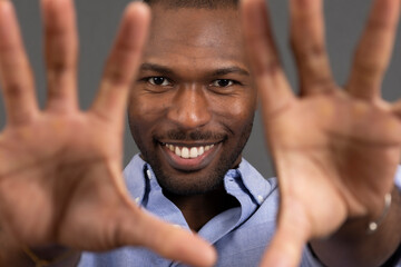 Smiling man framing face with hands in a close up studio portrait