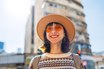 Young beautiful smiling woman in fashionable clothes and hat. Sexy carefree model posing outdoors on a sunny day. Positive brunette smiling on the street.