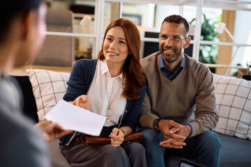 Happy couple receiving an offer from insurance agent during a meeting in the office.
