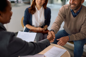 Close up of insurance agent handshaking with a couple during a meeting in the office.