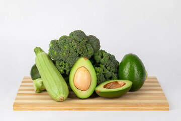 Assorted Fresh Vegetables on Wooden Cutting Board – Avocado, Broccoli, Red Cabbage, Zucchini on White Background