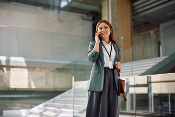 Happy corporate manager communicating over her smartphone in office.