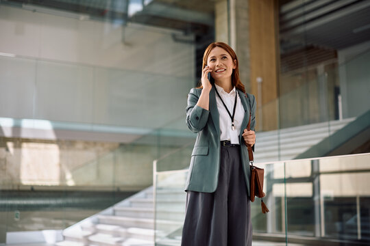 Happy corporate manager communicating over her smartphone in office.