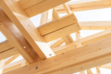 Close-up view of wooden beams and joints in a roof under construction, showcasing structural...